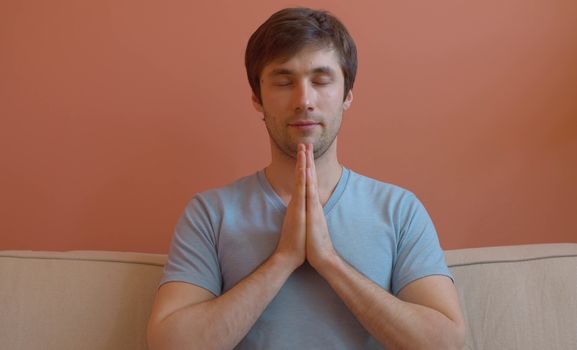 Portrait of young meditating man on pink background. Close up. The concept of meditation, relaxation, yoga, stress relief and inner peace and quiet