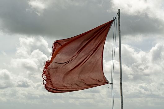 Slightly tatty red flag flying over Salisbury Plain in Wiltshire warning of army activity in the military controlled area.  