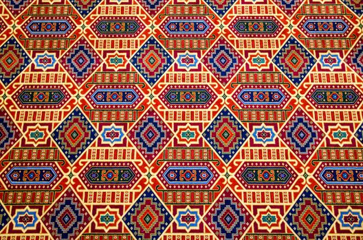 Ornate carpet with intricate colourful design viewed head on.