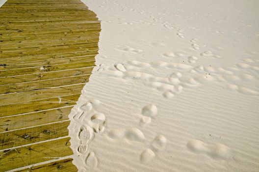 Sandy beach encroaching on a wooden boardwalk.  Monte Gordo seaside resort, Algarve Coast, Portugal.