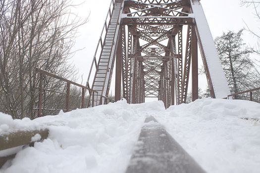 Winter landscape. Metall red bridge over the frozen river