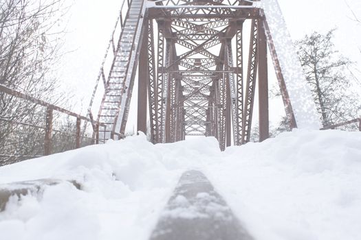 Winter landscape. Metall red bridge over the frozen river