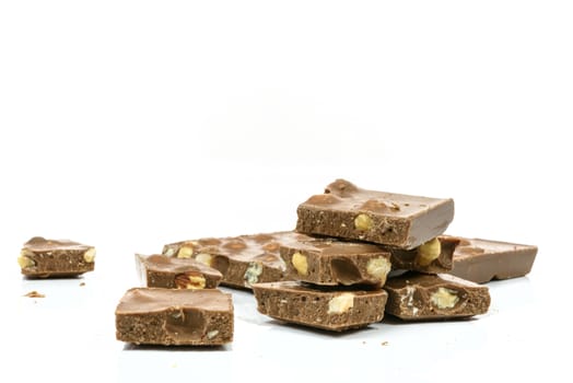 Stack of chocolate pieces with nuts in close-up and isolated on white background with copy space place.