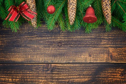 Christmas decoration concept - spruce branches with cones and Christmas ornaments on an old wooden vintage planks with copy space ( high details).