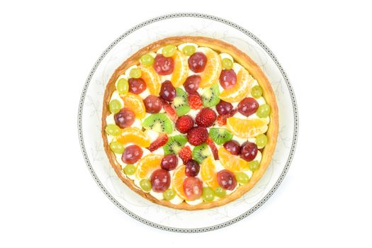 Top view of a fresh homemade multi-fruit tart cake on a plate and isolated on a white background.