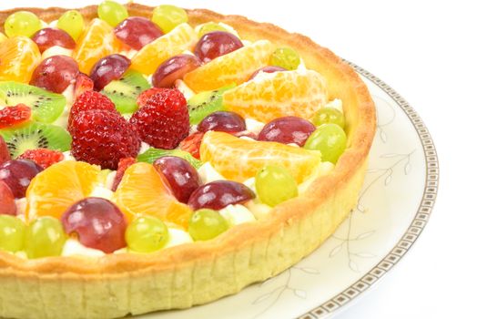 Fresh homemade multi fruit tart cake on a plate and isolated on a white background in closeup.