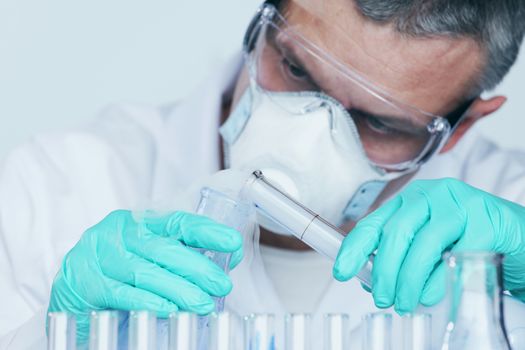 Mature male researcher carrying out scientific research in a lab, Chemistry experiments close up