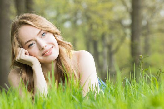 Happy smiling young woman laying on the green grass