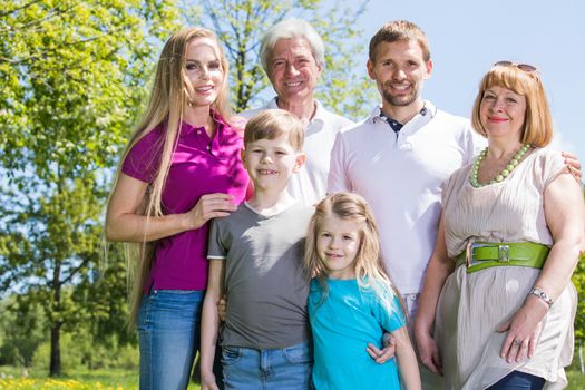 Multigeneration family portrait outdoors. Happy parents with two children and grandparents in summer park