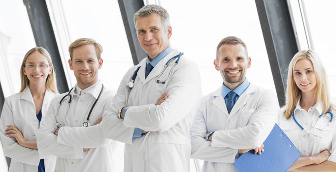 Team of medical professionals looking at camera, smiling, arms crossed