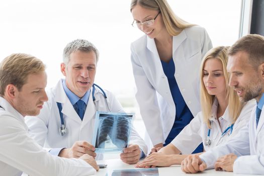 Team of experts doctors examining X-ray report on hospital office meeting