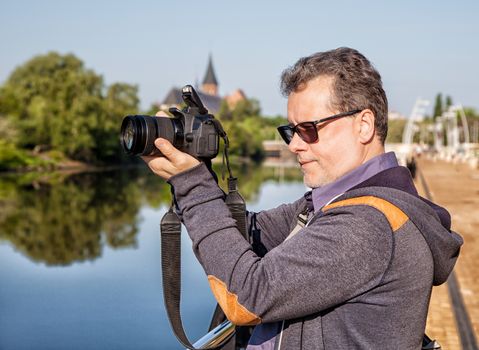 elderly man photographs the landscape on the waterfront on summer day