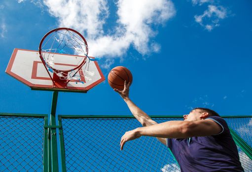 young man playing basketball in the courtyard on a sunny summer day