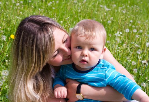 young mother plays with her son on the green grass