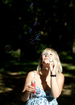 young pregnant woman blowing soap bubbles outdoor