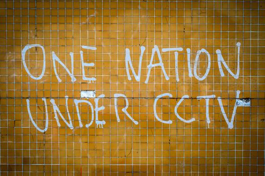 Grungy Graffiti On A Wall In The UK Saying One Nation Under CCTV