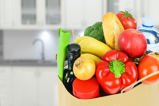 Grocery shopping concept image - Eco friendly paper shopping bag filled with various food products in the kitchen.