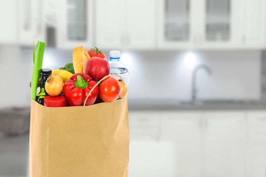 Grocery shopping concept image - Eco friendly paper shopping bag filled with various food products in the kitchen.