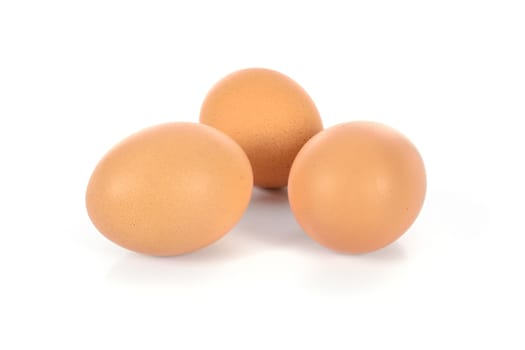 Three brown eggs in closeup and isolated on a white background.