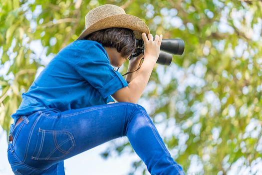 Close up Young asian woman short hair wear hat and hold binocular in grass field countryside Thailand