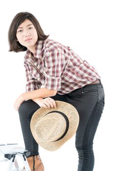 Young pretty woman in a cowboy hat and plaid shirt posing in studio with isolated on white background