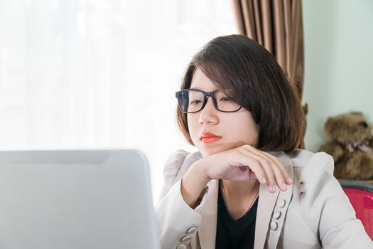 Woman teenage short hair in smart casual wear working on laptop while sit near window in home office