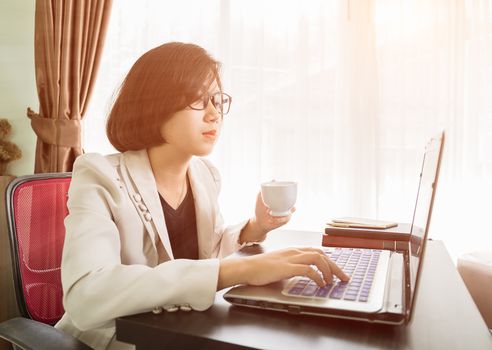 Woman teenage short hair in smart casual wear working on laptop while sit near window in home office