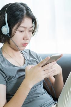 Close up young asian woman short hair listening music from mobile phone on the couch