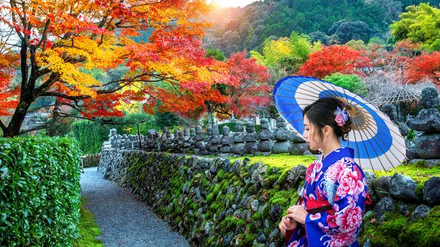 Asian woman wearing japanese traditional kimono in autumn park.