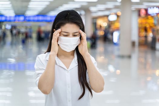 A woman with headache wearing medical mask to protect against coronavirus.