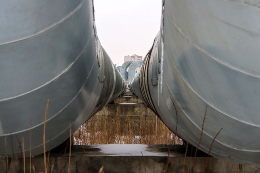 Two metal pipes with clearance departing into the distance. House on background.