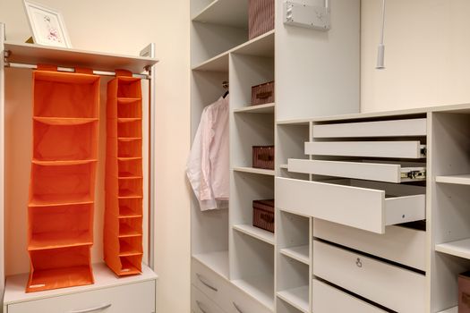 Empty wardrobe room with shelves, cabinets and other storage systems.