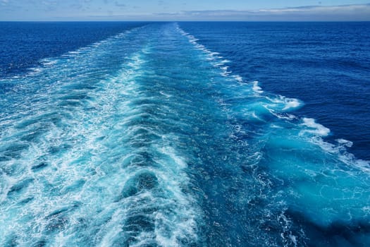 A Cruise ship wake on a beautiful sunny day with white clouds and blue seas on the Atlantic Ocean.