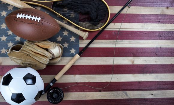 Various sport equipment for baseball, football, soccer and fishing on vintage wooden USA flag 