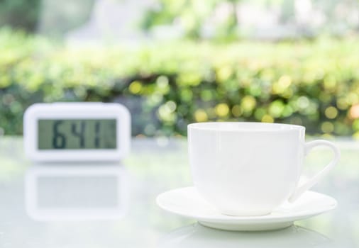 Close up Coffee cup on table at office with digital clock