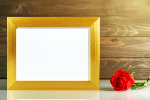 Picture mock up with golden frame and red roses flowers on table with copy space