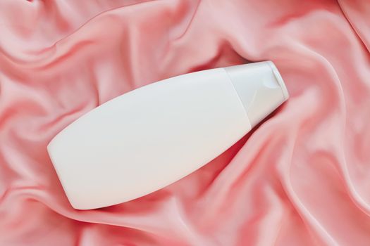 Blank label cosmetic container bottle as product mockup on pink silk background, hygiene and healthcare