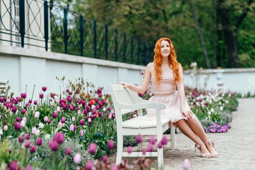 red-haired young girl walking in a park between trees and architectural objects