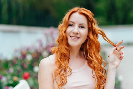 red-haired young girl walking in a park between trees and architectural objects