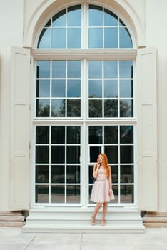 red-haired young girl walking in a park between trees and architectural objects