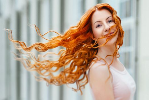 red-haired young girl walking in a park between trees and architectural objects