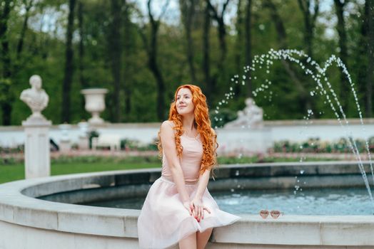 red-haired young girl walking in a park between trees and architectural objects