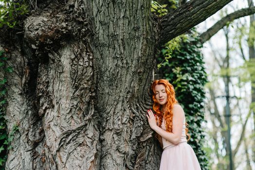 red-haired young girl walking in a park between trees and architectural objects