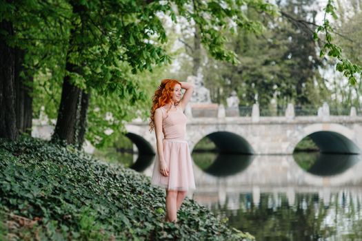 red-haired young girl walking in a park between trees and architectural objects