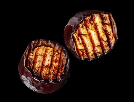 Two pieces of grilled eggplant black background rotate