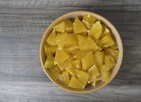 View of sliced oranges in a bowl, on wooden background.