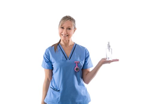 Friendly nurse wearing blue scrubs holding hand sanitizer or other medical or pharmaceutical product in palm of hand and smiling