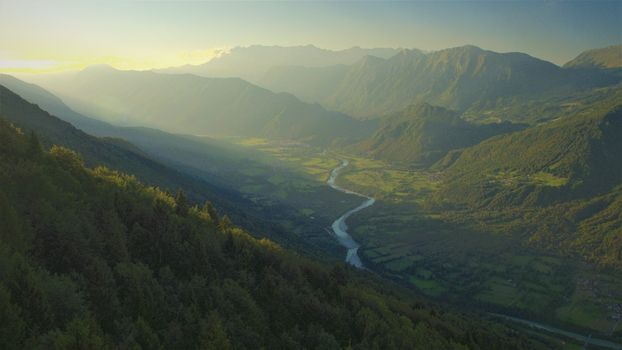 AERIAL VIEW. Meandering river winding through mountain valley in misty morning