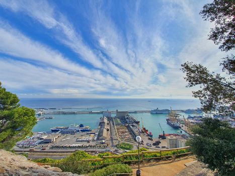 Aerial view from Montjuic Hill over industrial port of Barcelona, docked ships, cranes and containers