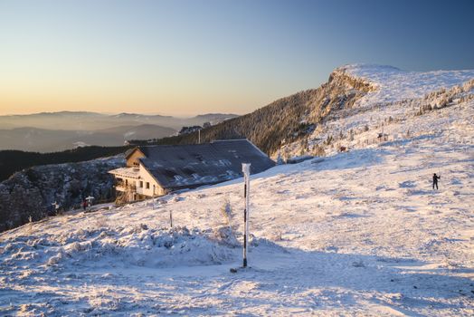 Frozen mountain scene at sunrise, chalat and tourists in Romanian Carpathians.